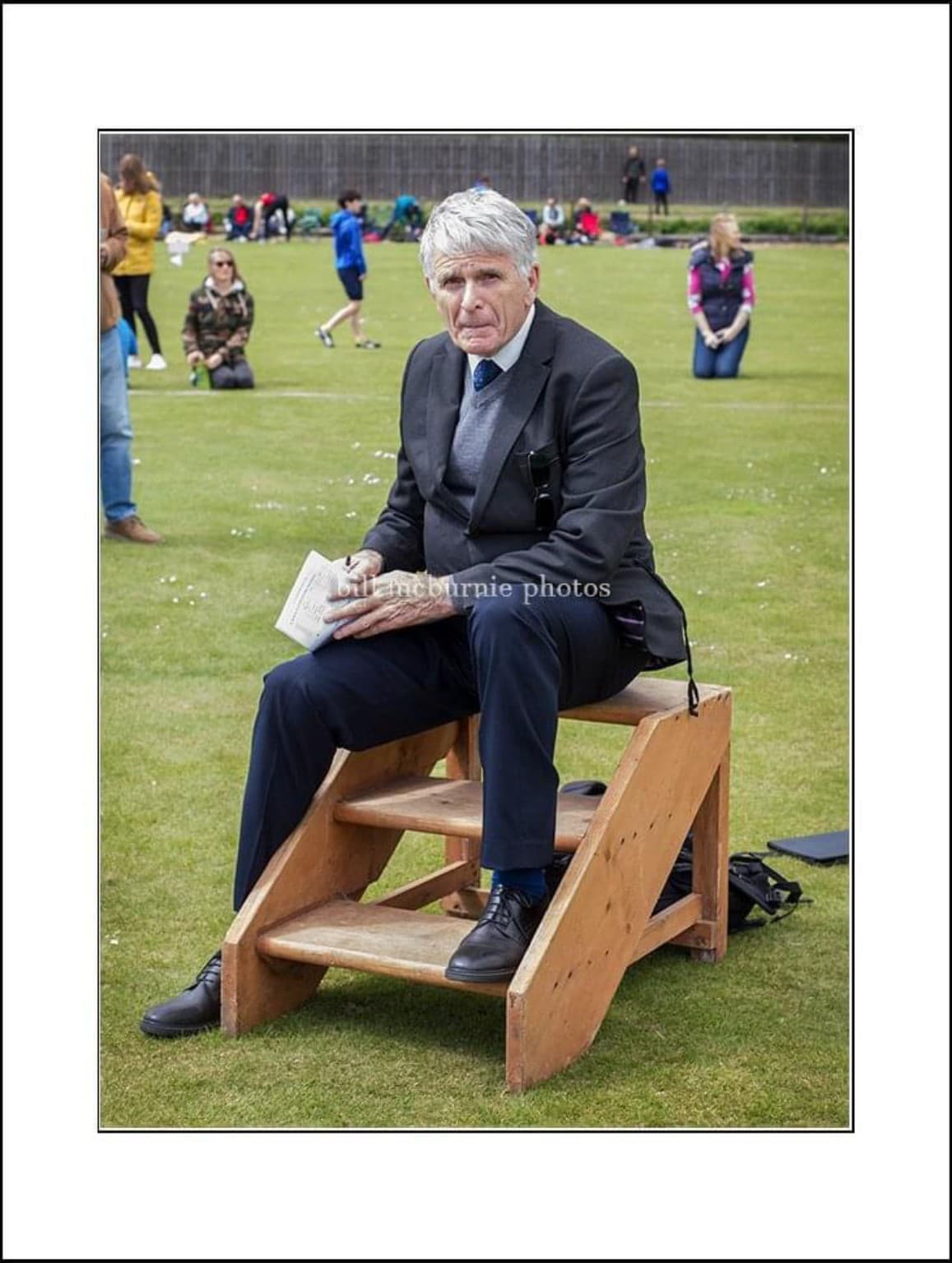 Robert Inglis seated at an athletics event in his later coaching career